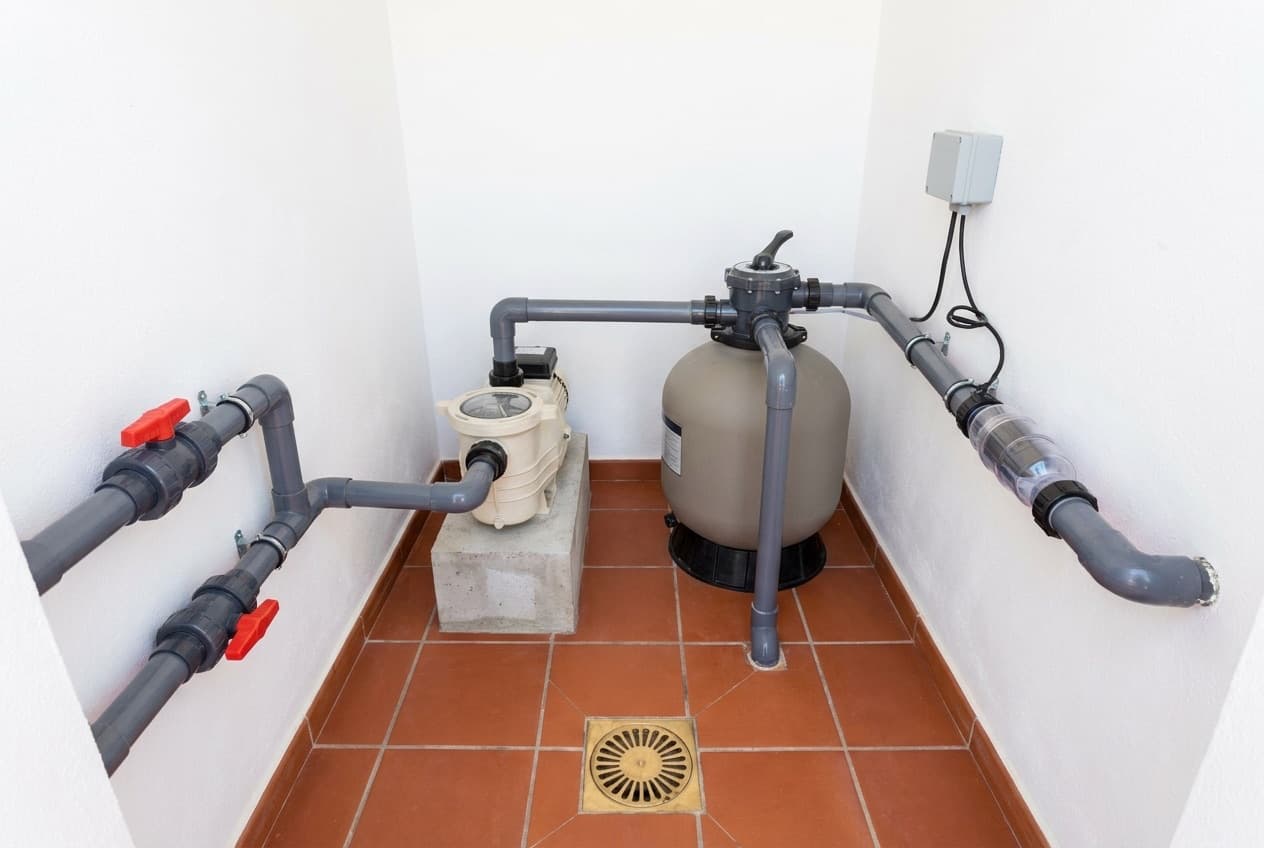 Casa das máquinas de piscina arrumada com filtro de areia, bomba, eletrólise de sal e tubagem em PVC com válvulas
